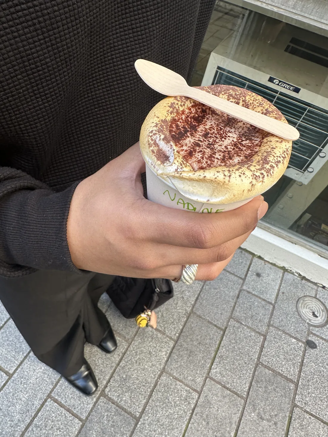 Aaditha holding a dusted tiramisu-style coffee cup on the street