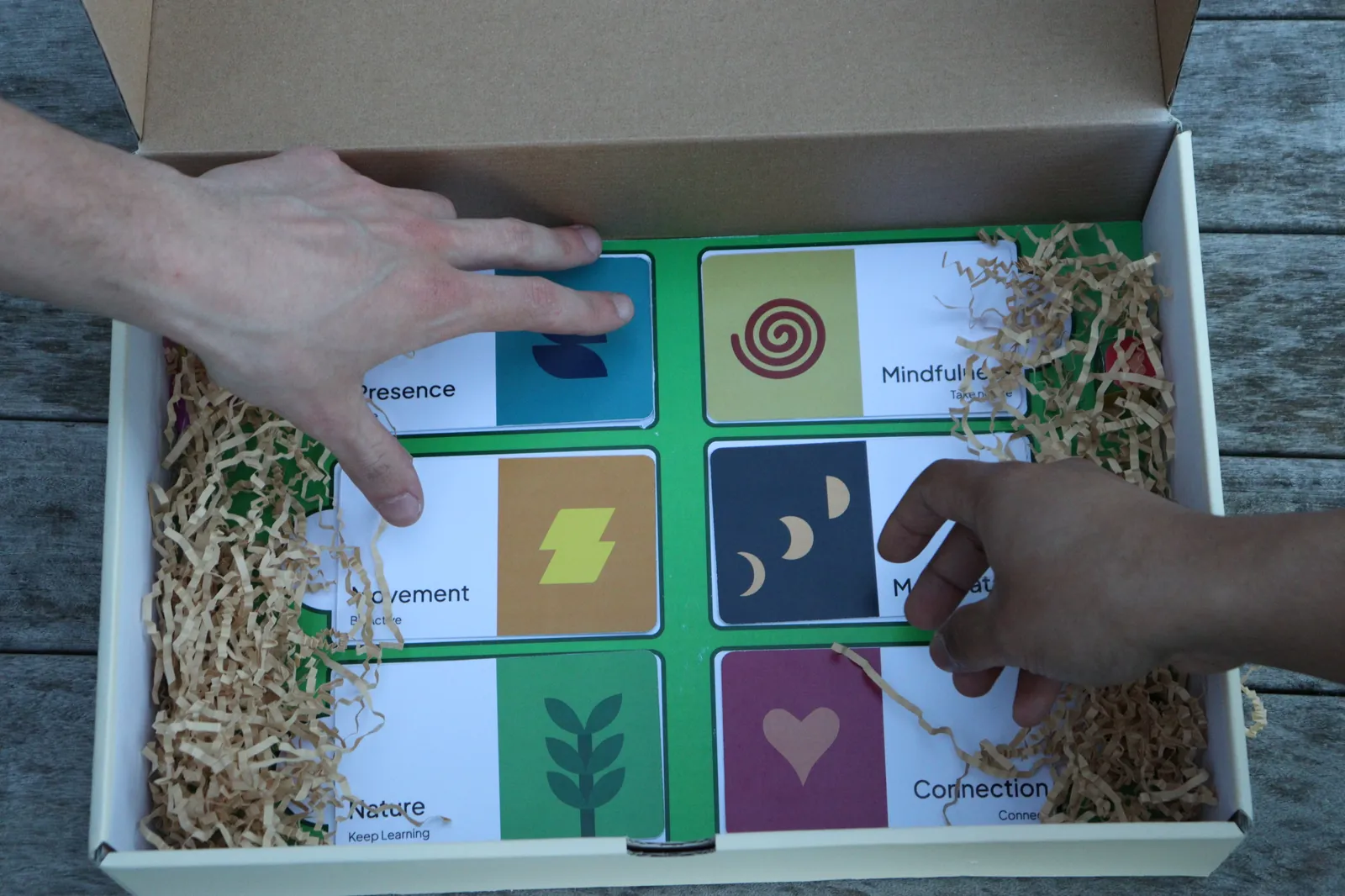 Hands arranging the colourful Bud theme cards inside the box